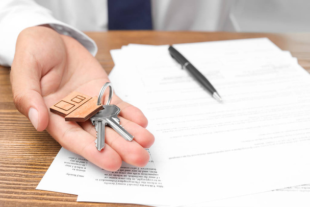 Agente imobiliário com chaves e documentos à mesa
 - Foto, Imagem