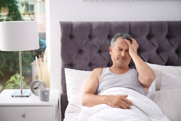 Man suffering from headache after sleep in bed. Uncomfortable pillow - Fotografie, Obrázek