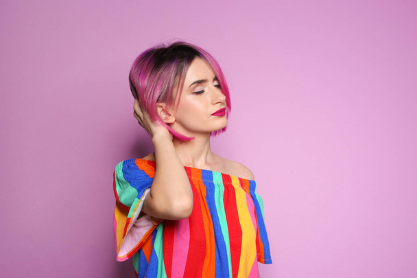 Young woman with trendy hairstyle against color background - Фото, зображення