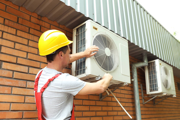 Male technician fixing air conditioner outdoors - Zdjęcie, obraz