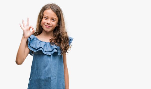 Μελαχρινή κορίτσι Ισπανόφωνος φοράει φόρεμα τζιν κάνει εντάξει πινακίδα με τα δάχτυλα, εξαιρετική σύμβολο - Φωτογραφία, εικόνα