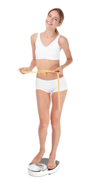 Happy slim woman with measuring tape and bathroom scales on white background. Weight loss diet results - Φωτογραφία, εικόνα