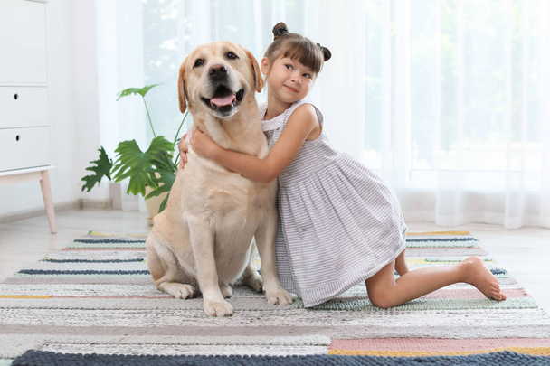 Adorable yellow labrador retriever and little girl at home - Foto, imagen