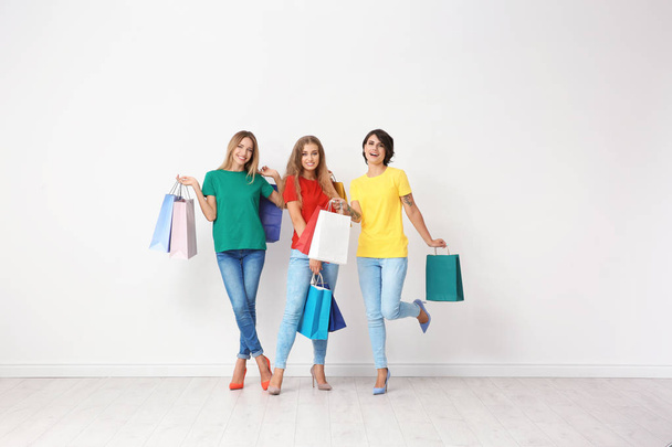 Group of young women with shopping bags near light wall - Foto, Imagem