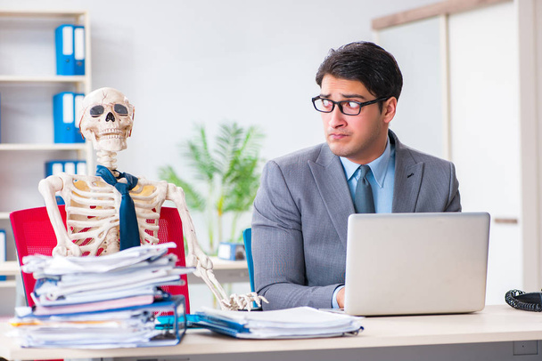 Homme d'affaires travaillant avec squelette dans le bureau - Photo, image