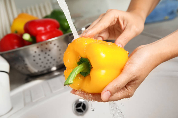 Woman washing paprika pepper in kitchen sink, closeup - Zdjęcie, obraz
