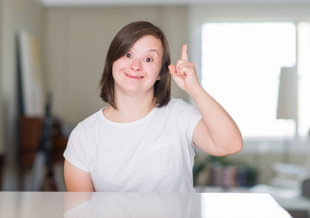 Down syndrome Kobieta w domu zaskoczył pomysł lub pytanie palcem wskazującym z szczęśliwy twarz, numer jeden - Zdjęcie, obraz