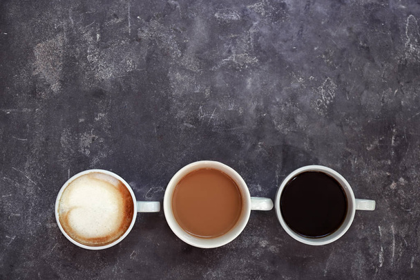 Cups of fresh aromatic coffee on grey background, top view - 写真・画像