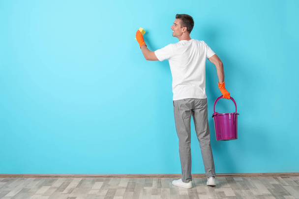 Man in gloves cleaning color wall with rag - Photo, image