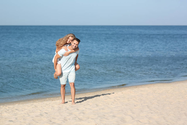 Happy young couple at beach on sunny day - Foto, immagini