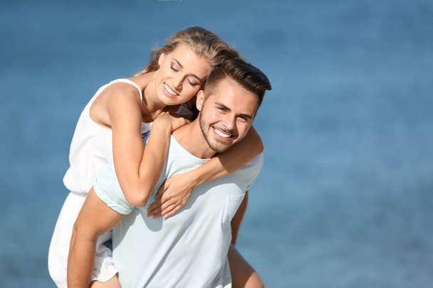 Happy young couple at beach on sunny day - Фото, изображение