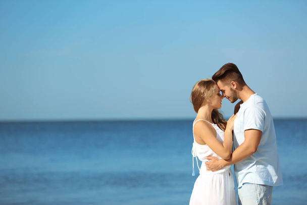 Happy young couple at beach on sunny day - Foto, imagen