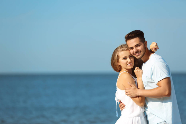 Happy young couple at beach on sunny day - Photo, Image
