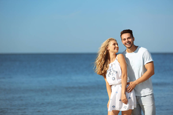 Glückliches junges Paar am Strand an sonnigem Tag - Foto, Bild