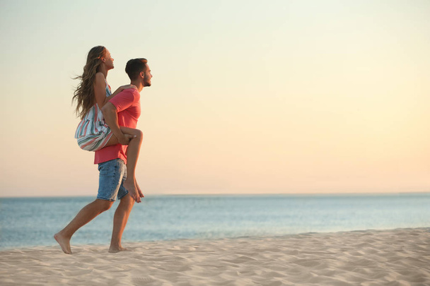 Joyeux jeune couple jouant ensemble sur la plage
 - Photo, image