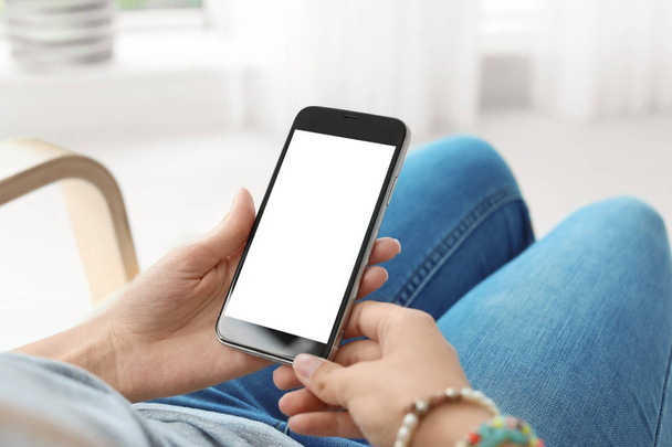 Woman holding smartphone with blank screen on blurred background. Mockup for design - Photo, Image