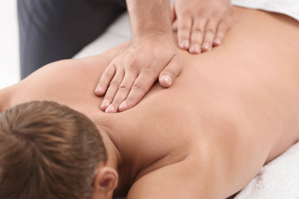 Relaxed man receiving back massage in wellness center - Foto, afbeelding