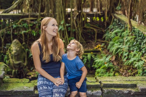 Mom and son travelers discovering Ubud forest in Monkey forest, Bali Indonesia. Traveling with children concept. - Fotó, kép
