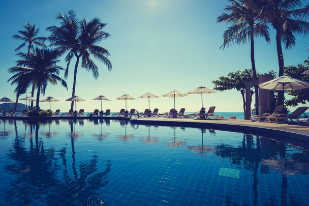 Hermosa playa tropical y el mar con sombrilla y silla alrededor de la piscina en el complejo hotelero para viajes y vacaciones - Foto, Imagen