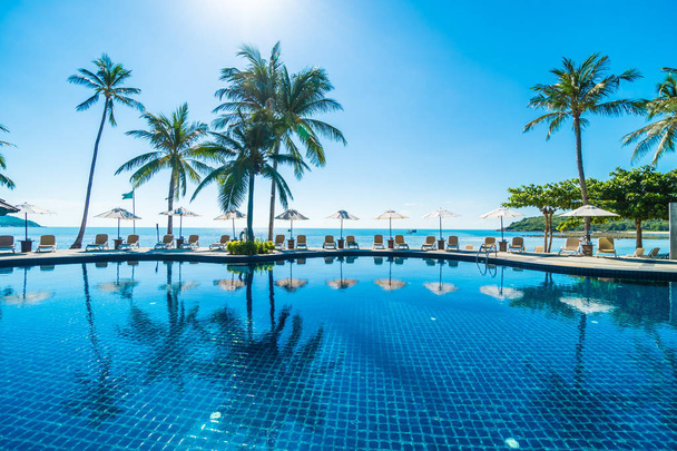 Belle plage tropicale et mer avec parasol et chaise autour de la piscine dans la station hôtelière pour les voyages et les vacances - Photo, image