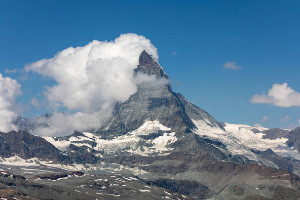 moon shining over the famous matterhorn with clouds and blue sky in HDR, switzerland - Photo, image