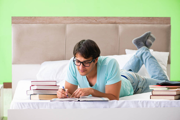 Étudiant se préparant pour les examens à la maison dans la chambre couchée sur le lit - Photo, image