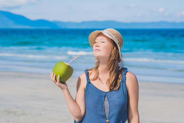 Aantrekkelijke jonge vrouw kokoswater drinken op het strand. - Foto, afbeelding