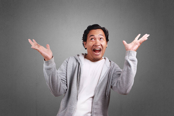 Jovem asiático homem vestindo uma jaqueta, sorrindo e rindo, Ambos de palma aberta
 - Foto, Imagem