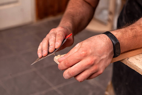 Close-up A male carpenter in work clothes restoring a wooden bar  with wax and a spatula on a wooden table - Photo, Image