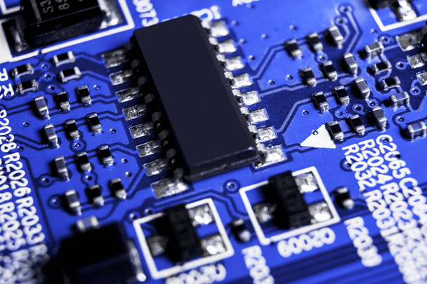 Macro shot of a Circuitboard with resistors microchips and electronic components. Computer hardware technology. Integrated communication processor in blue tones. Semiconductor. PCB. Closeup - Φωτογραφία, εικόνα