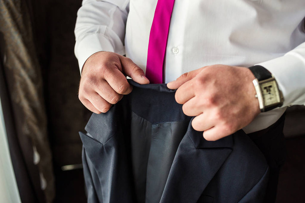 Επιχειρηματίας φοράει ένα σακάκι, αρσενικά χέρια closeup, γαμπρός ετοιμάζεται το πρωί πριν από την τελετή του γάμου - Φωτογραφία, εικόνα
