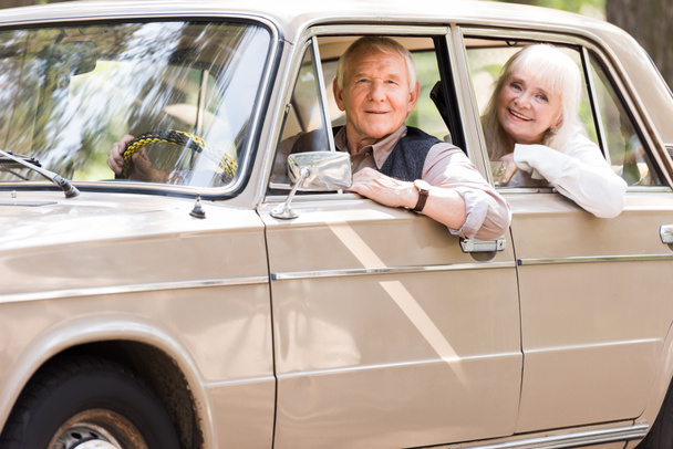 side view of attractive senior couple in beige car - Photo, Image