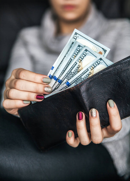 In the women's hands is the leather wallet with a wad of hundred dollars. Business offer. Beautiful manicure - Fotoğraf, Görsel