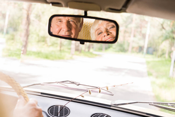 Вид счастливой пожилой пары в заднем окне винтажного автомобиля
  - Фото, изображение
