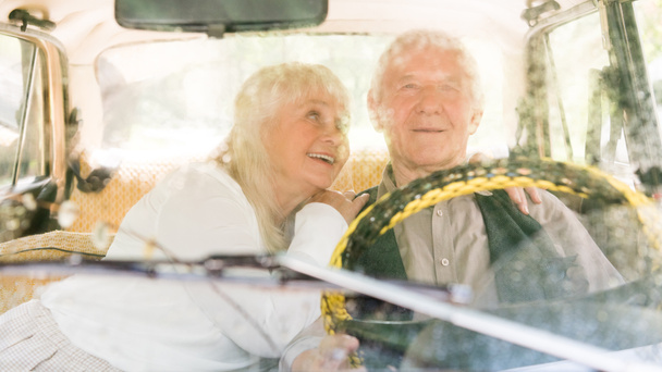 view through windshield of senior couple sitting in retro car  - 写真・画像