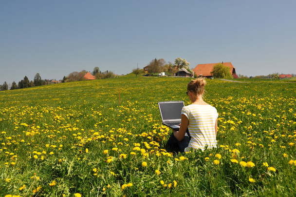 Menina com um laptop no prado da primavera
 - Foto, Imagem
