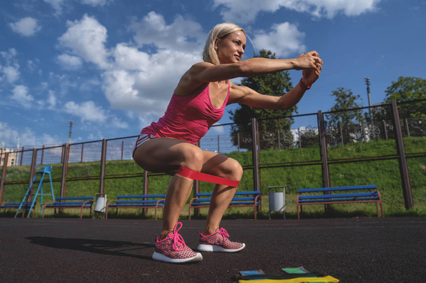 Mladá sportovní žena dělá cvičení s gumičkou venku - Fotografie, Obrázek