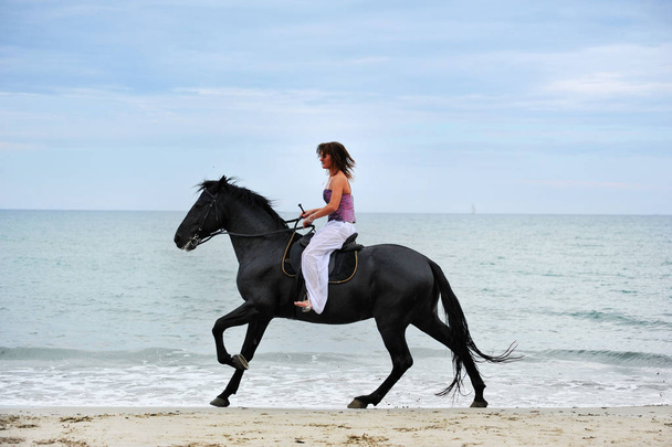 hevonen ja nainen laukkaa rannalla
 - Valokuva, kuva