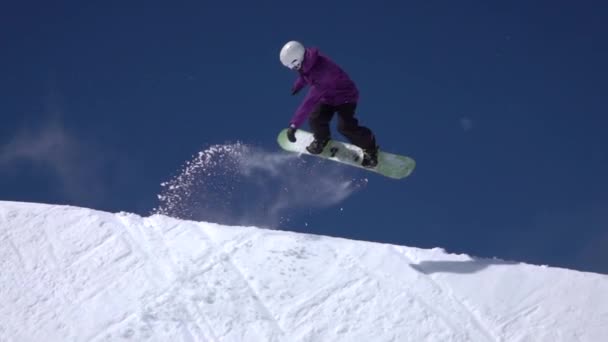 Slow Motion: Mladí pro snowboardista na koni rampě v big mountain snow parku, skákání vysoké zdi u-rampa, provádění triků a střídání s drapáky v slunných zimních - Záběry, video