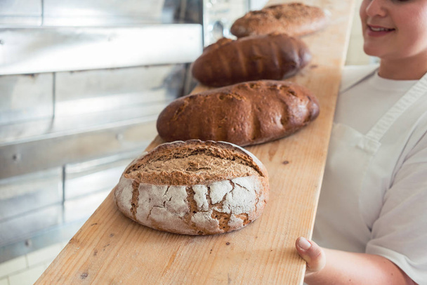 Fresh bread on a board in bakehouse of bakery - Foto, imagen