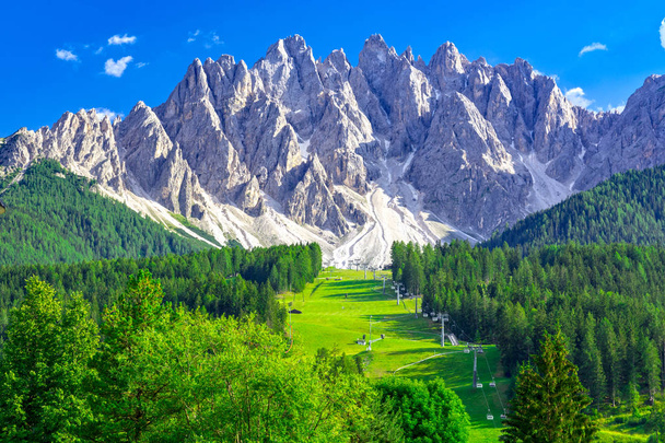 Sommerlandschaft in den Dolomiten, Skipiste mit Seilbahn in San Candido mit Bergkette im Hintergrund - Foto, Bild
