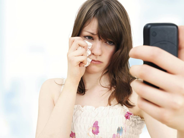Girl teenager holding mobile phone and crying  - Фото, изображение