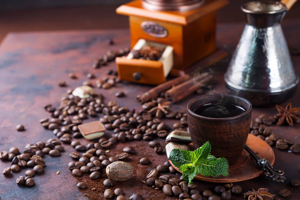 egy csésze kávét, menta, a bab és a fűszerek, amely mellett a terjedési mill, turka és darab csokoládé barna alapon. Hely, a szöveg másolása - Fotó, kép