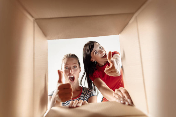 Women unpacking and opening carton box and looking inside - Foto, Imagem