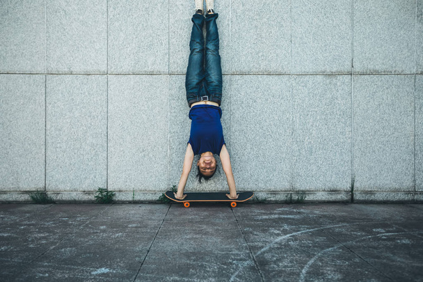 Sportswoman doing a handstand against a marble wall  - Фото, изображение