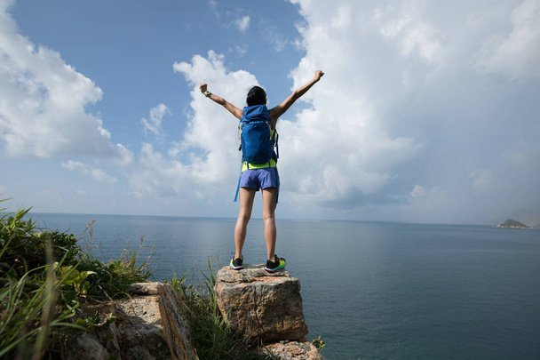 Woman enjoying nature with opened arms on seaside cliff edge - Φωτογραφία, εικόνα