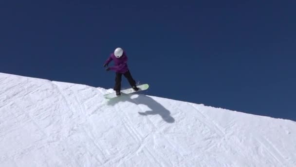 MOCIÓN LENTA: Joven snowboarder profesional montando la media tubería en un gran parque de nieve de montaña, saltando alto de la pared de la media tubería, realizando trucos y rotaciones con agarraderas en invierno soleado
 - Imágenes, Vídeo