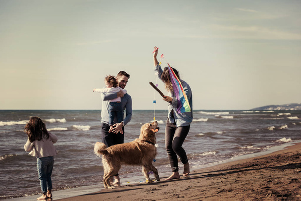 happy young family with kids having fun with a dog and  kite at beach during autumn day filter - Fotografie, Obrázek