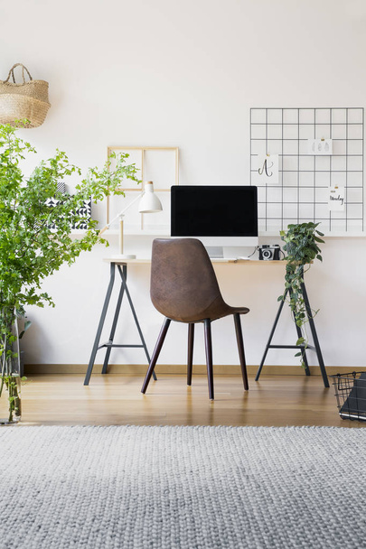 Inspirational organizer in a hipster workspace interior with a stylish, leather chair by a tall, industrial desk with a desktop computer - 写真・画像