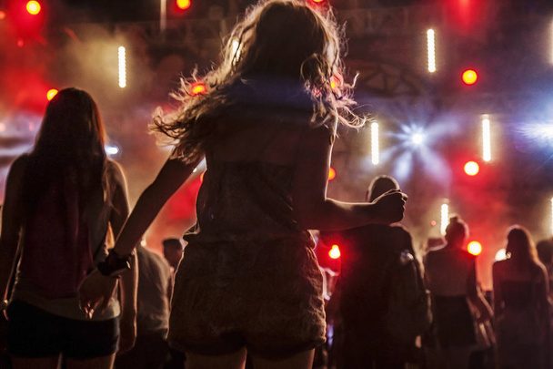 Tanzende Menschen bei nächtlicher Konzertparty, verschwommener Hintergrund - Foto, Bild